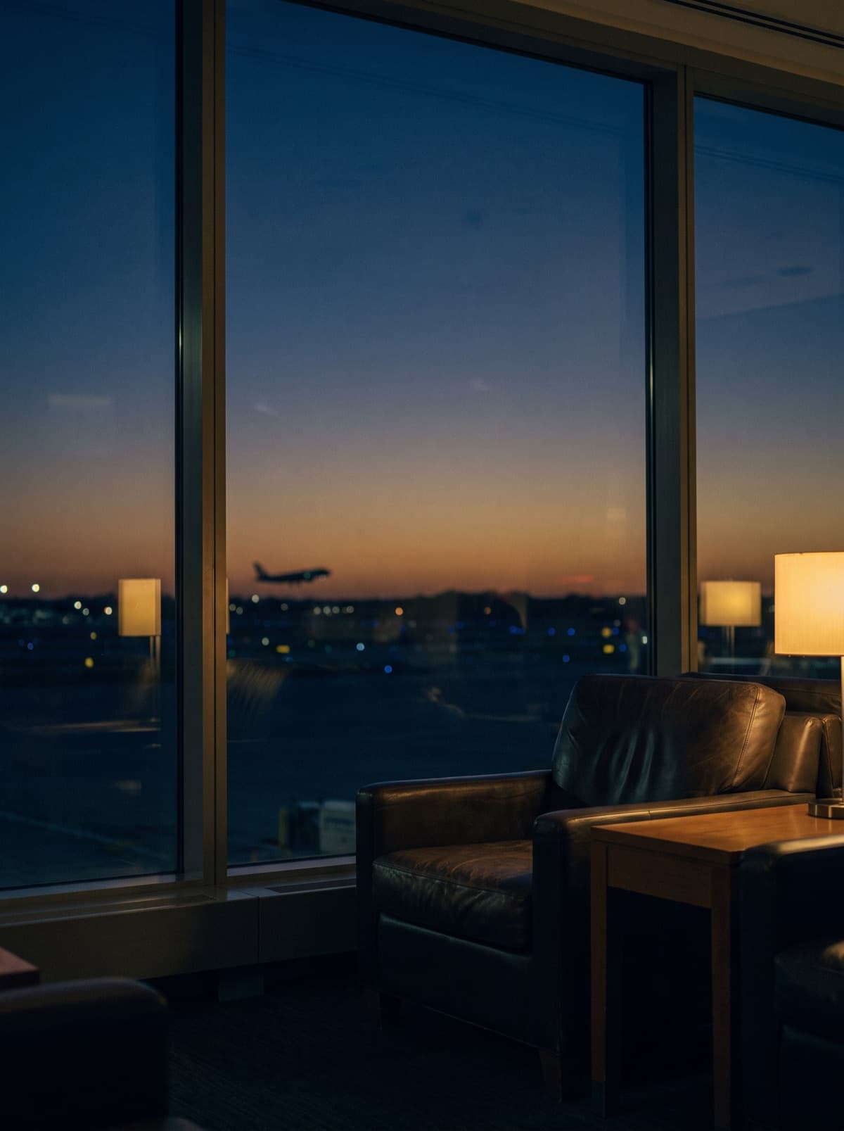 An airport window at dusk with distant runway lights