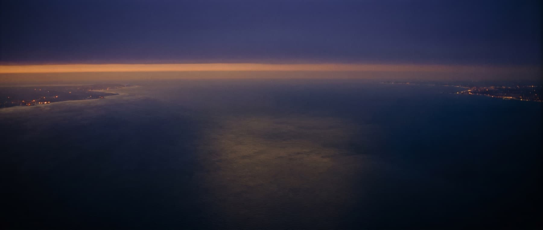 The Atlantic Ocean from above at dusk, a thin band of gold on the horizon